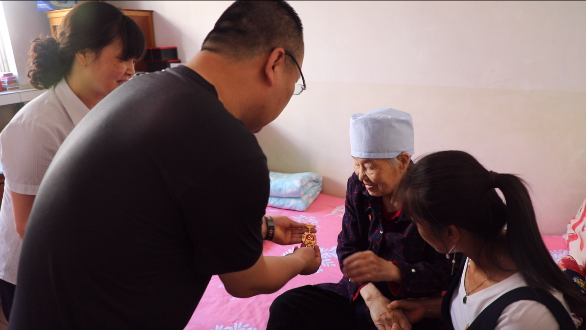 西峰區(qū)炮臺巷社區(qū)黨總支書記張永治為李秀芳頒發(fā)紀念章。梁博睿/攝