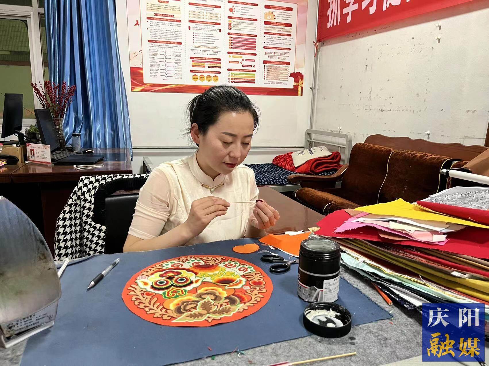 李慶英正在創(chuàng)作布貼畫作品。